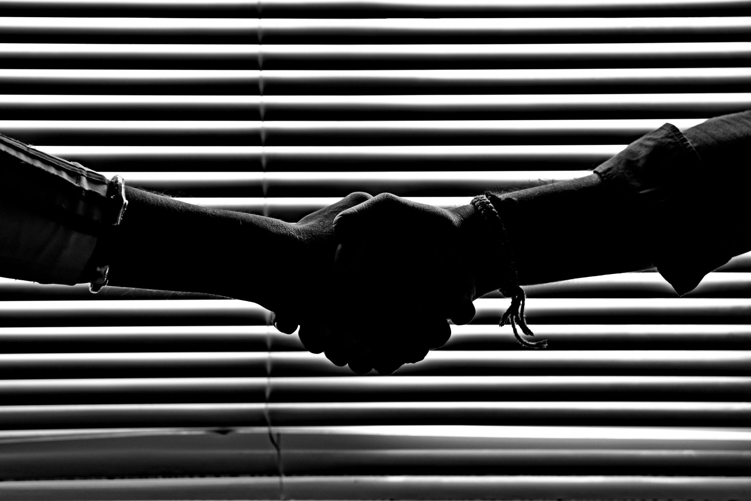 Poignée de main dans un cadre sombre illustrant la notion d’abus de confiance en droit pénal